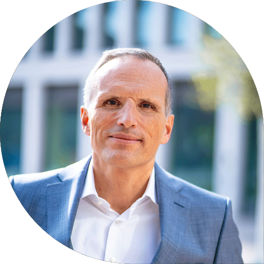 Porträt eines Mannes im hellblauen Anzug und weißem Hemd vor dem Hauptgebäude der Heidelberger Volksbank.